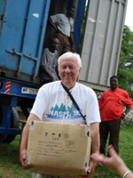 An E-Quip Africa volunteer stops to smile, as he helps to load the shipping container headed to Ghana, with donated computers and educational materials.